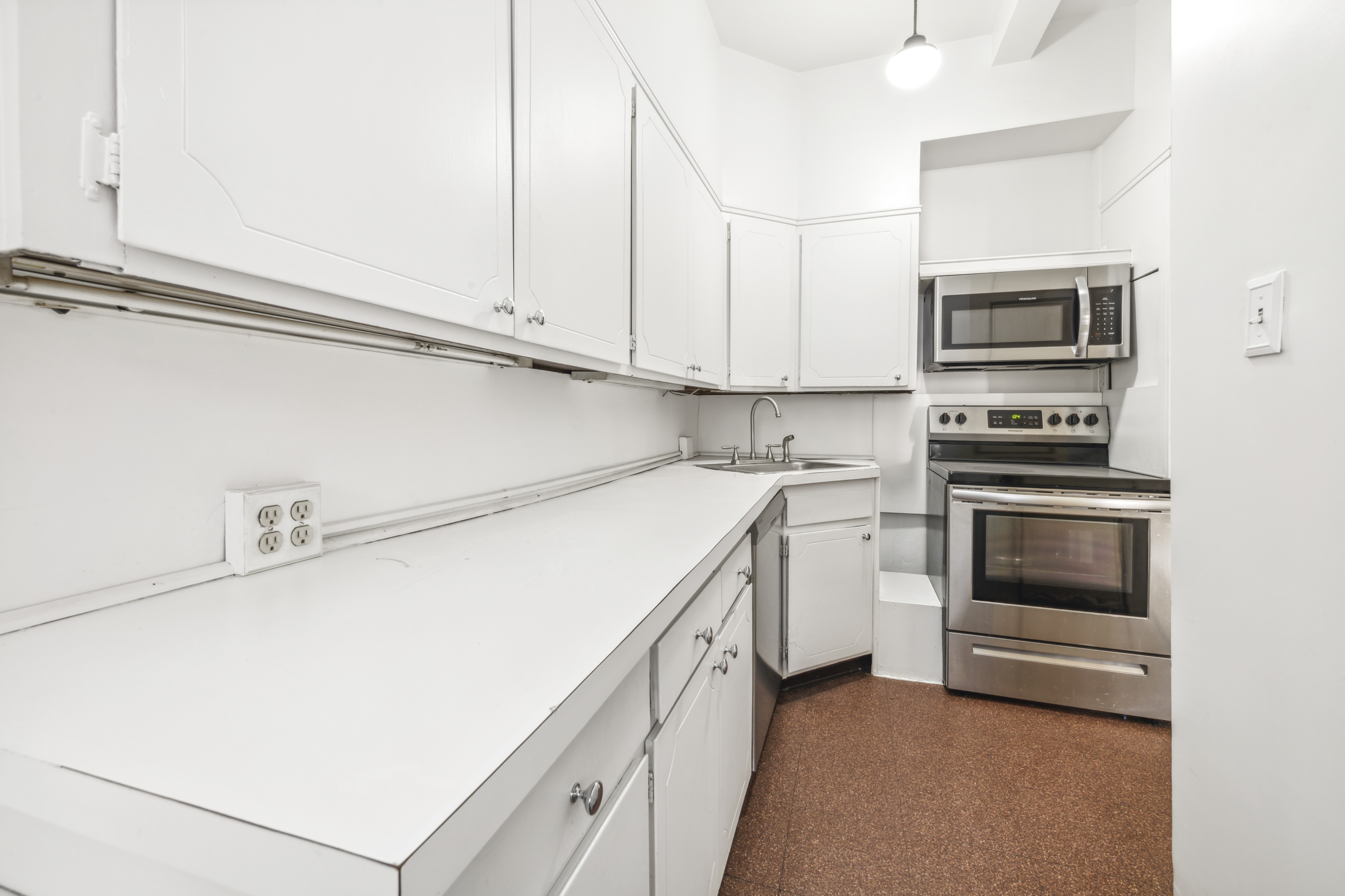 130 East 67th Street, Unit 9C Manhattan, NY 10065 - Photo 8 of 20 a kitchen with white cabinets and stainless steel appliances