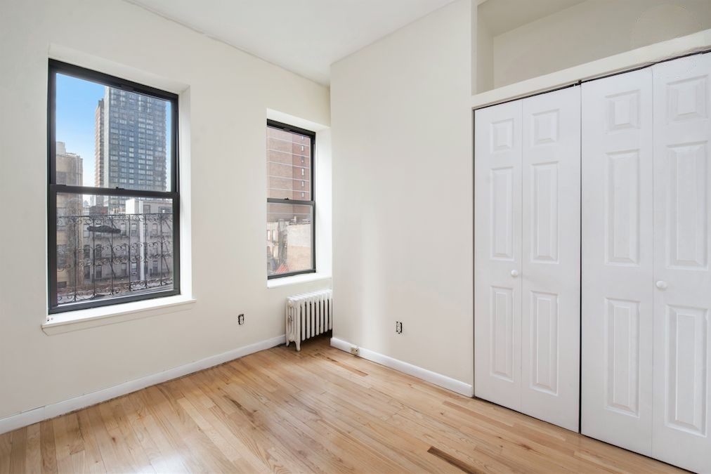 309 East 95th Street, Unit 27 Manhattan, NY 10128 - Photo 8 of 8 an empty room with wooden floor and windows