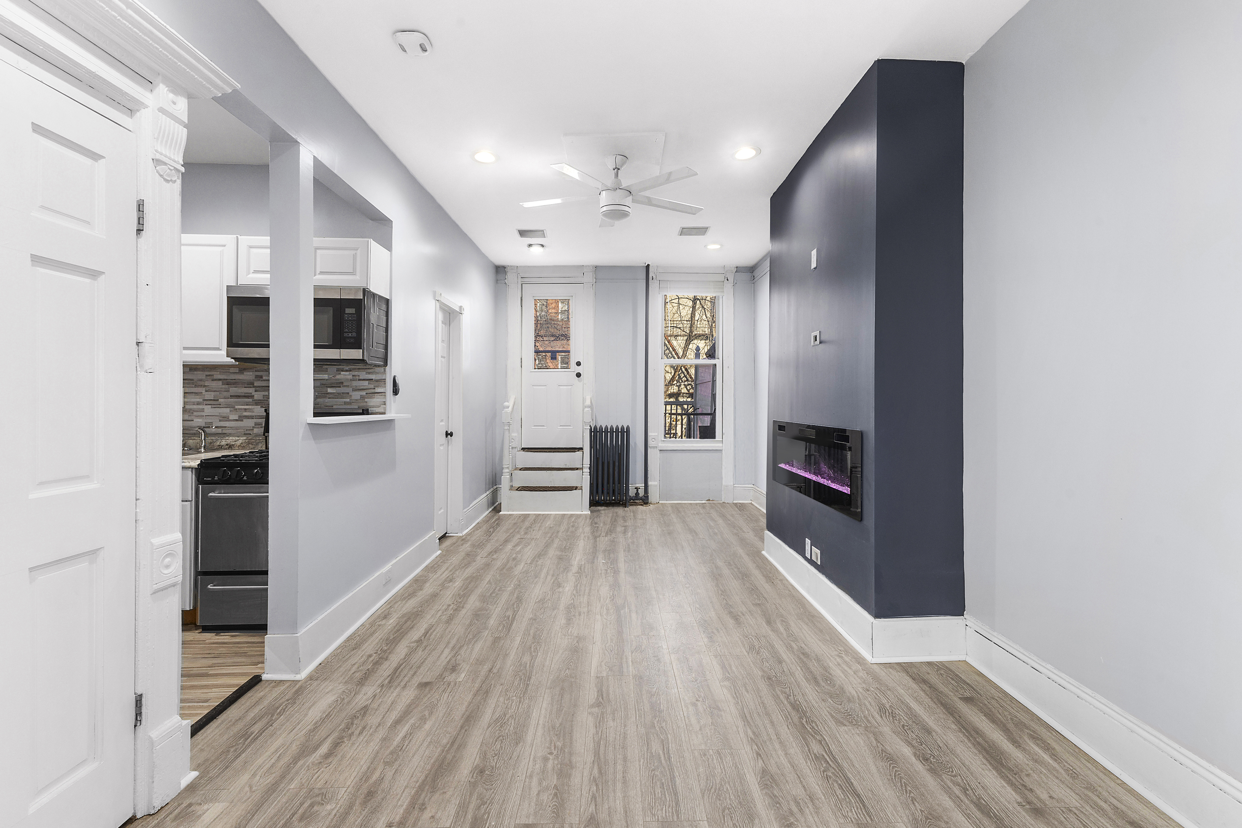 693 MacDonough Street, Unit 2 Brooklyn, NY 11233 - Photo 4 of 11 an empty room with wooden floor and a kitchen