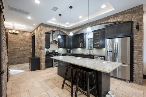 a kitchen with stainless steel appliances granite countertop a sink a stove and a refrigerator