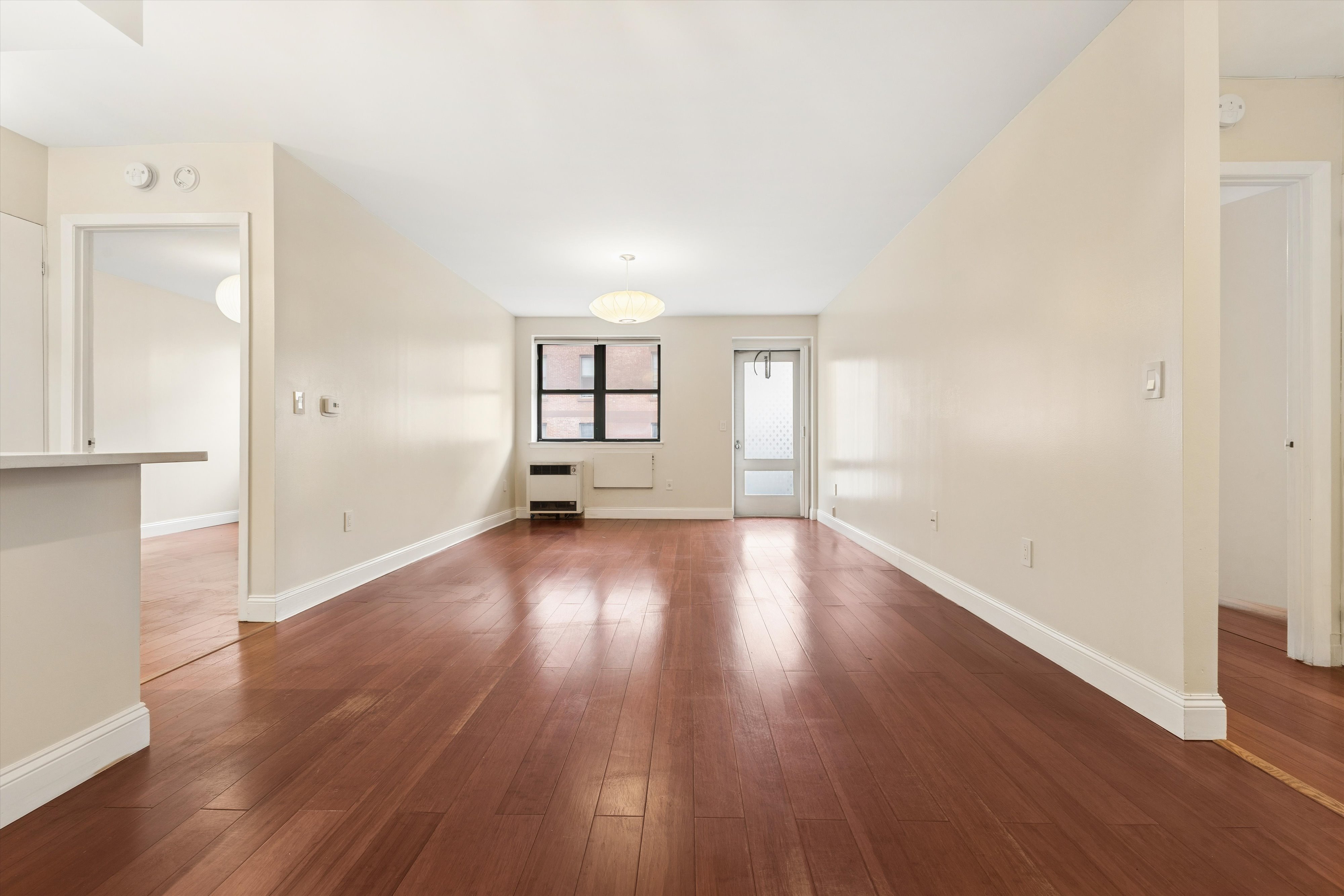 1919 Madison Avenue, Unit 418 Manhattan, NY 10035 - Photo 2 of 16 an empty room with wooden floor and windows