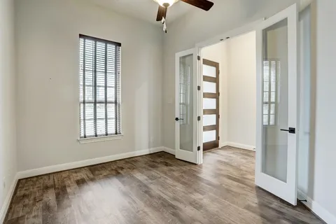 an empty room with wooden floor cabinet and windows