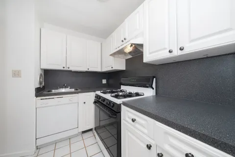 a kitchen with granite countertop white cabinets and white appliances