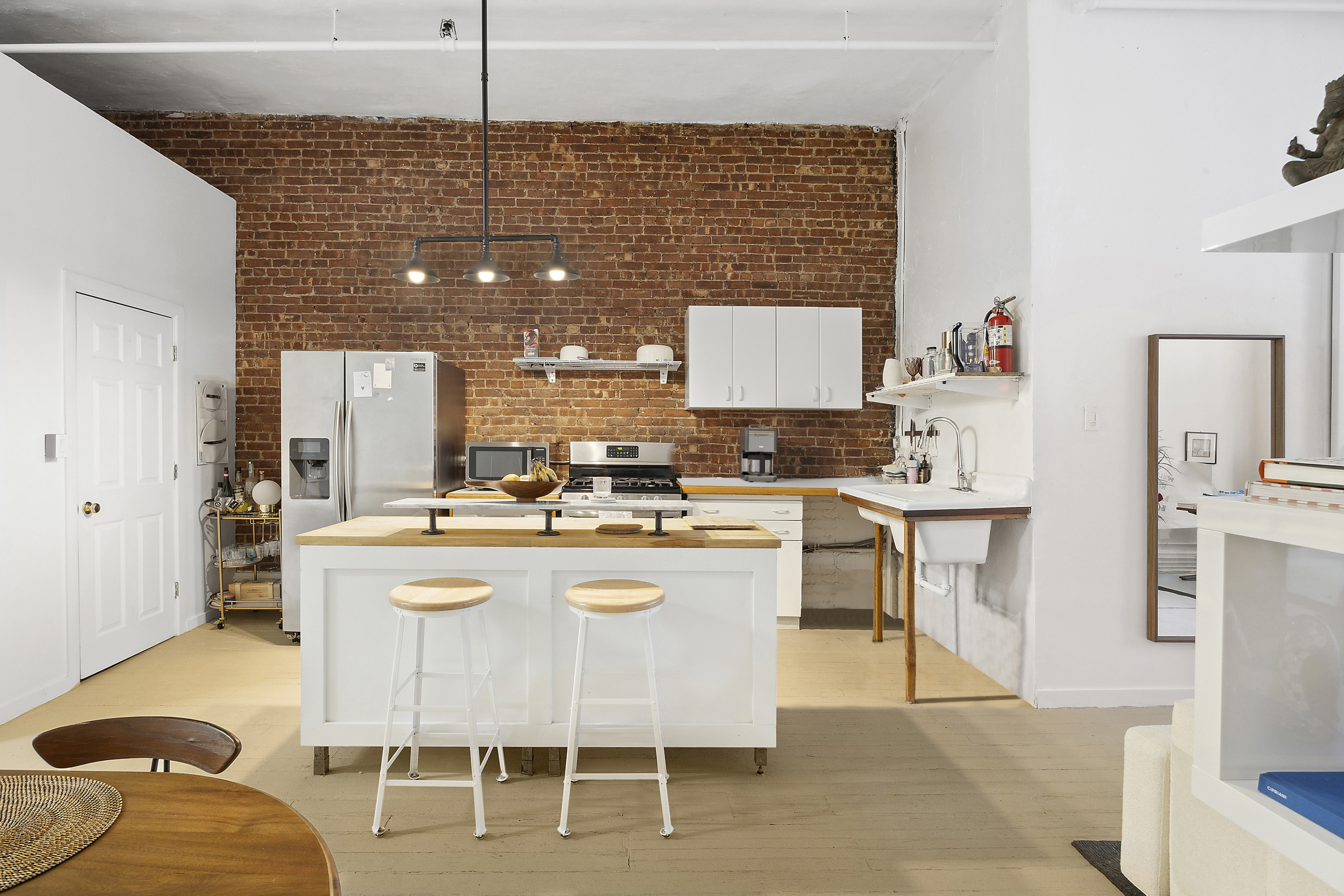 8 Greene Street, Unit 3 Manhattan, NY 10013 - Photo 3 of 7 a kitchen with kitchen island a dining table chairs cabinets and a sink
