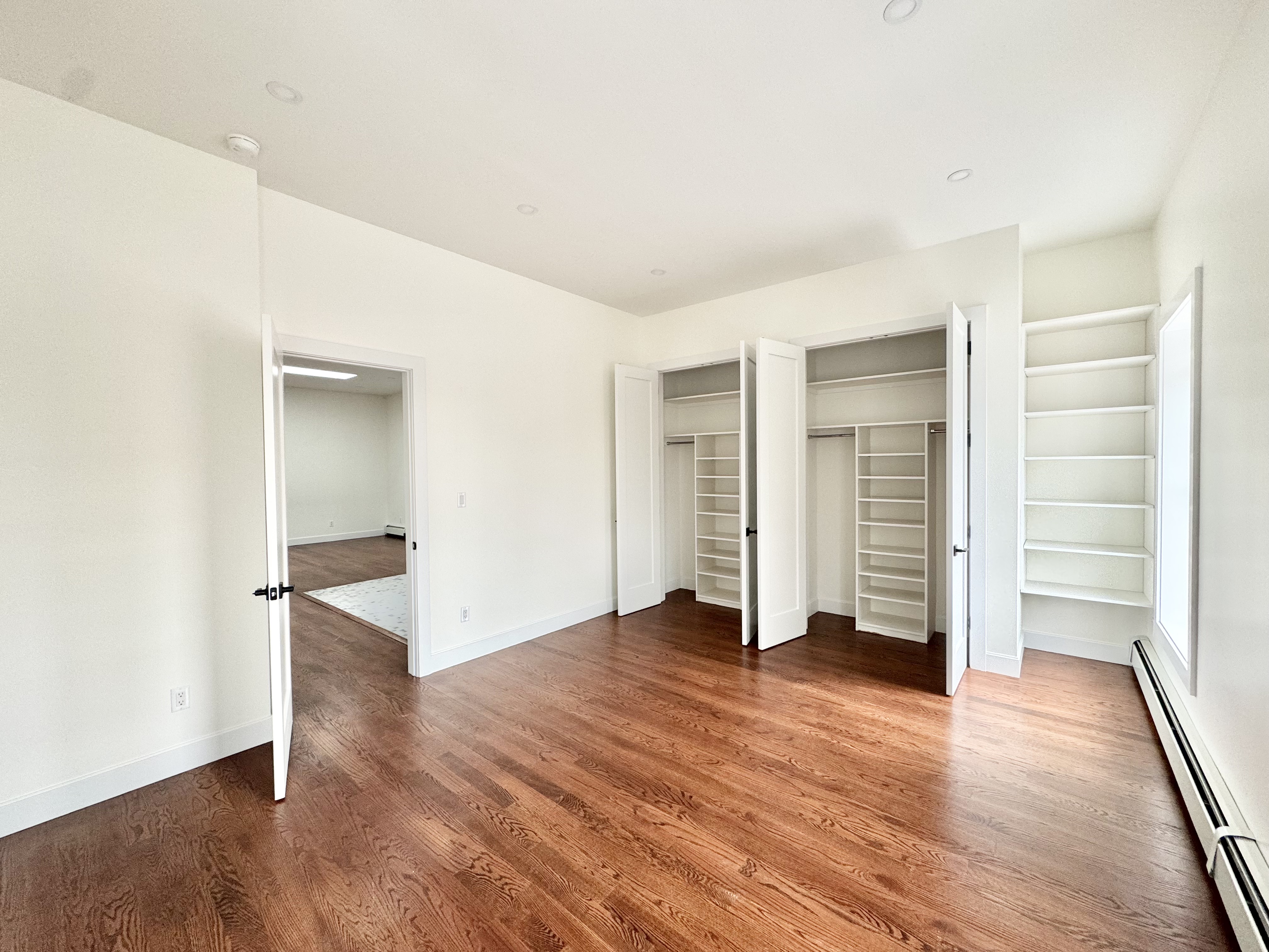 an empty room with wooden floor & closet area