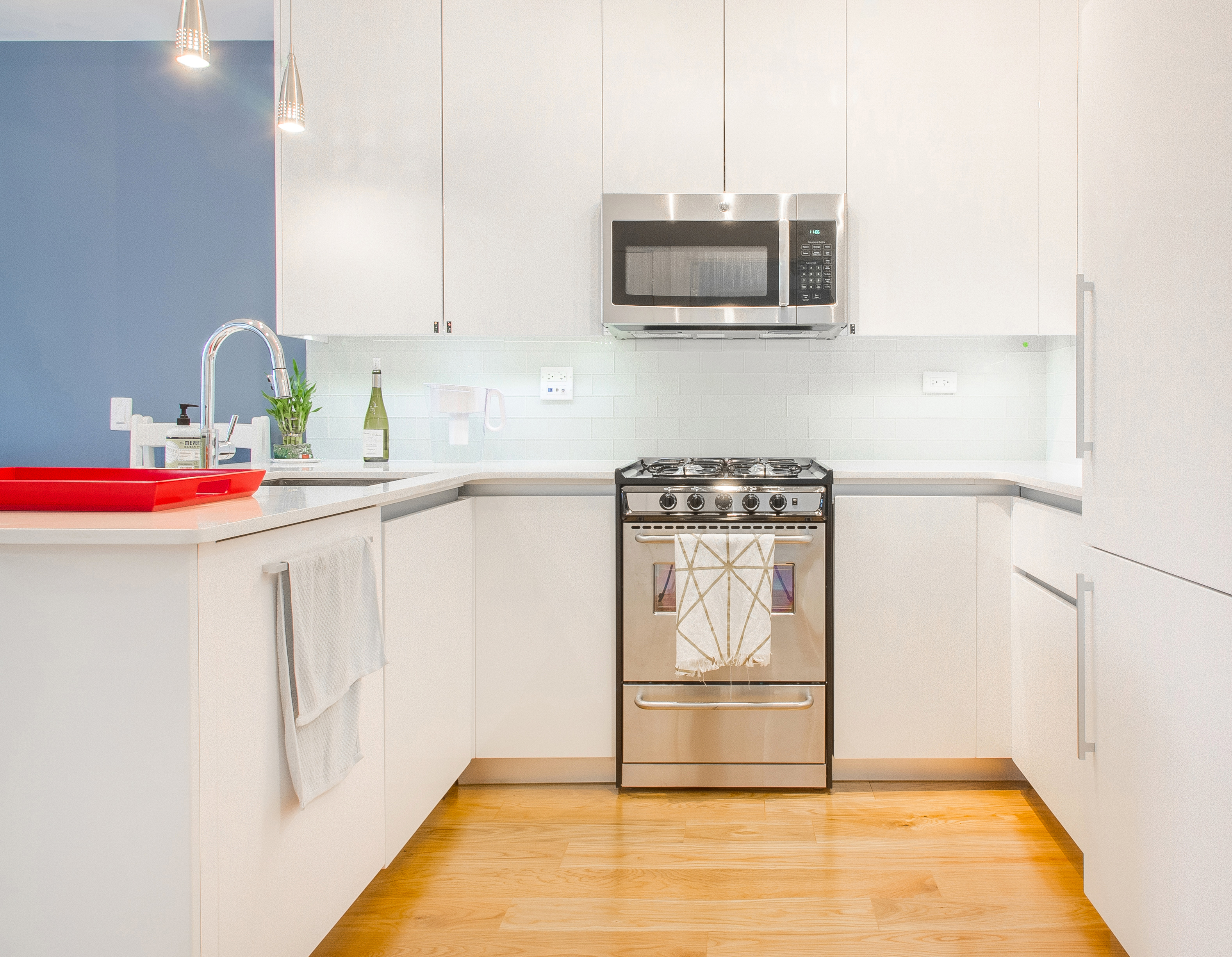 51 East 131st Street, Unit 6A Manhattan, NY 10037 - Photo 3 of 12 a kitchen with stainless steel appliances a stove a microwave and white cabinets