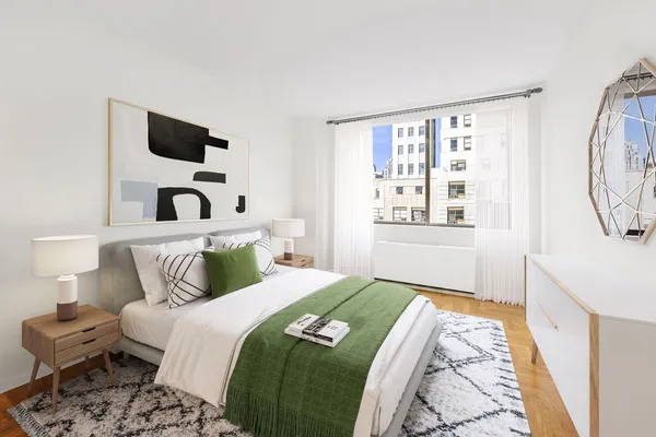 a bedroom with a bed a mirror on the wall and a window