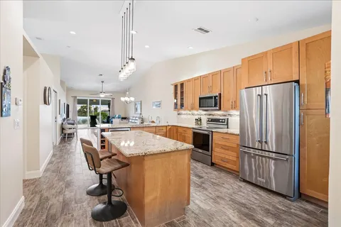 a kitchen with stainless steel appliances granite countertop a refrigerator a sink dishwasher a stove and a refrigerator with wooden floor