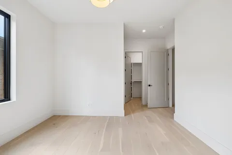 an empty room with chandelier fan and kitchen view