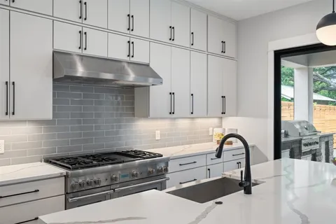 a kitchen with granite countertop a stove a sink dishwasher and white cabinets with wooden floor