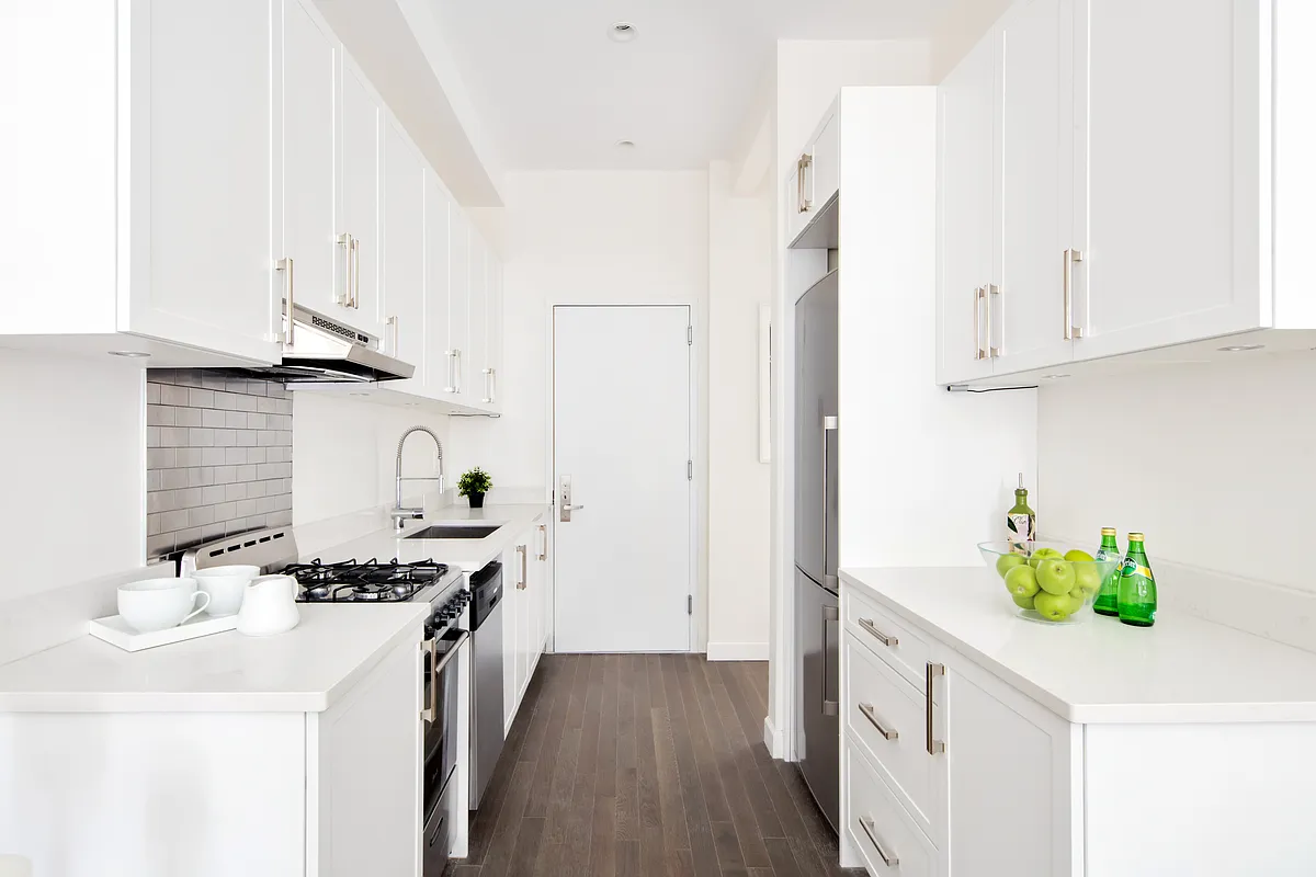 44 East End Avenue, Unit 3C Manhattan, NY 10028 - Photo 2 of 13 a kitchen with stainless steel appliances a white cabinets wooden floors and a sink
