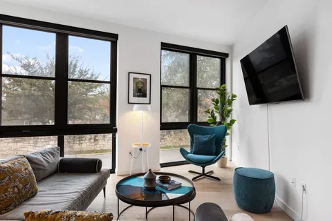 a living room with furniture a flat screen tv and a floor to ceiling window