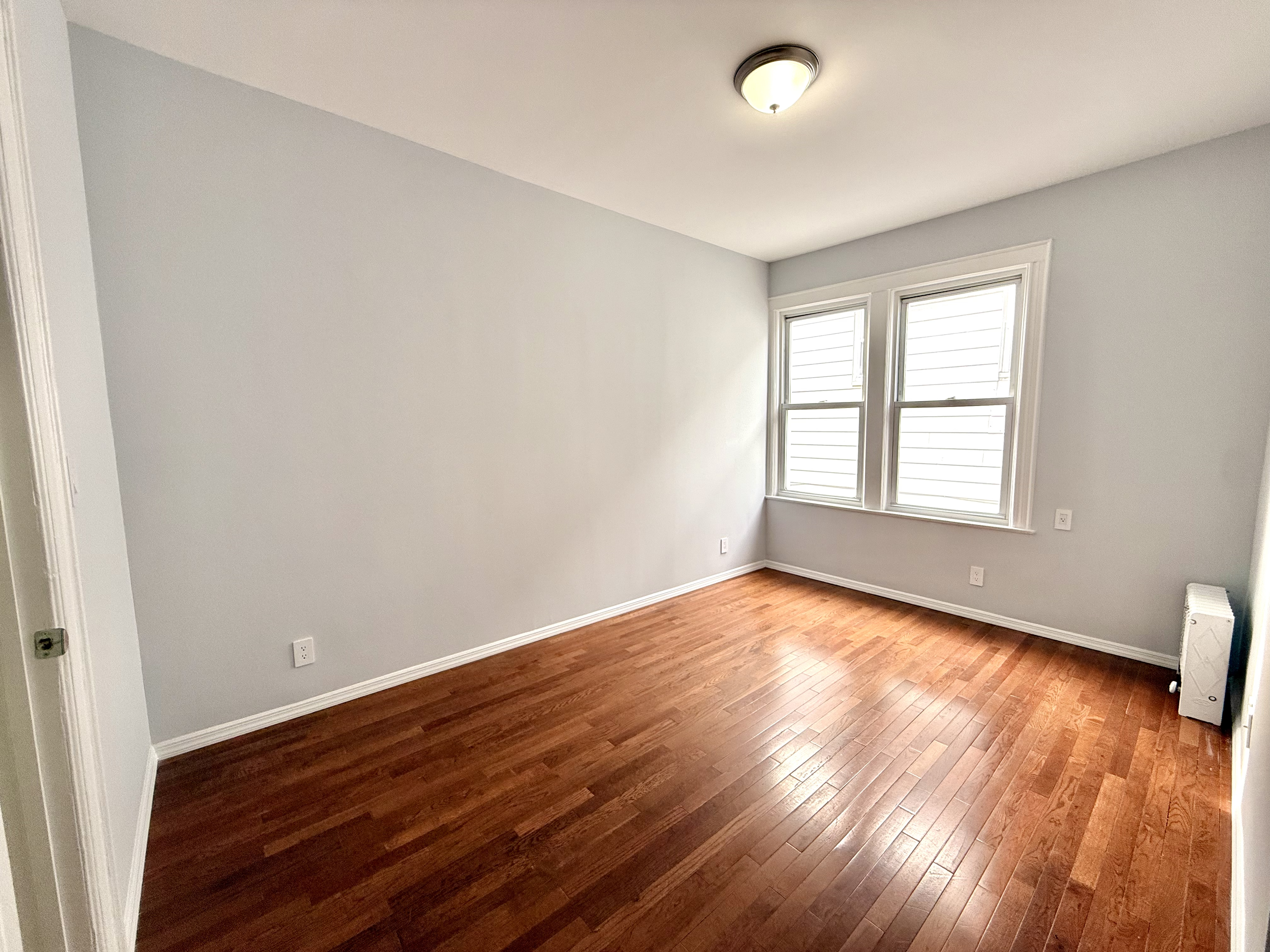 1675 85th Street, Unit 2R Brooklyn, NY 11214 - Photo 2 of 6 wooden floor in an empty room with a window