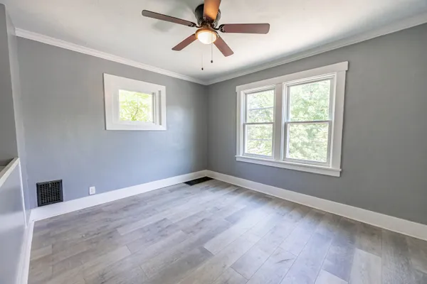 a view of an empty room with window and wooden floor