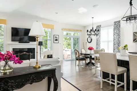 a dining room with wooden floor a chandelier a glass table and chairs