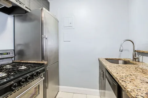 a kitchen with granite countertop a sink stove and refrigerator