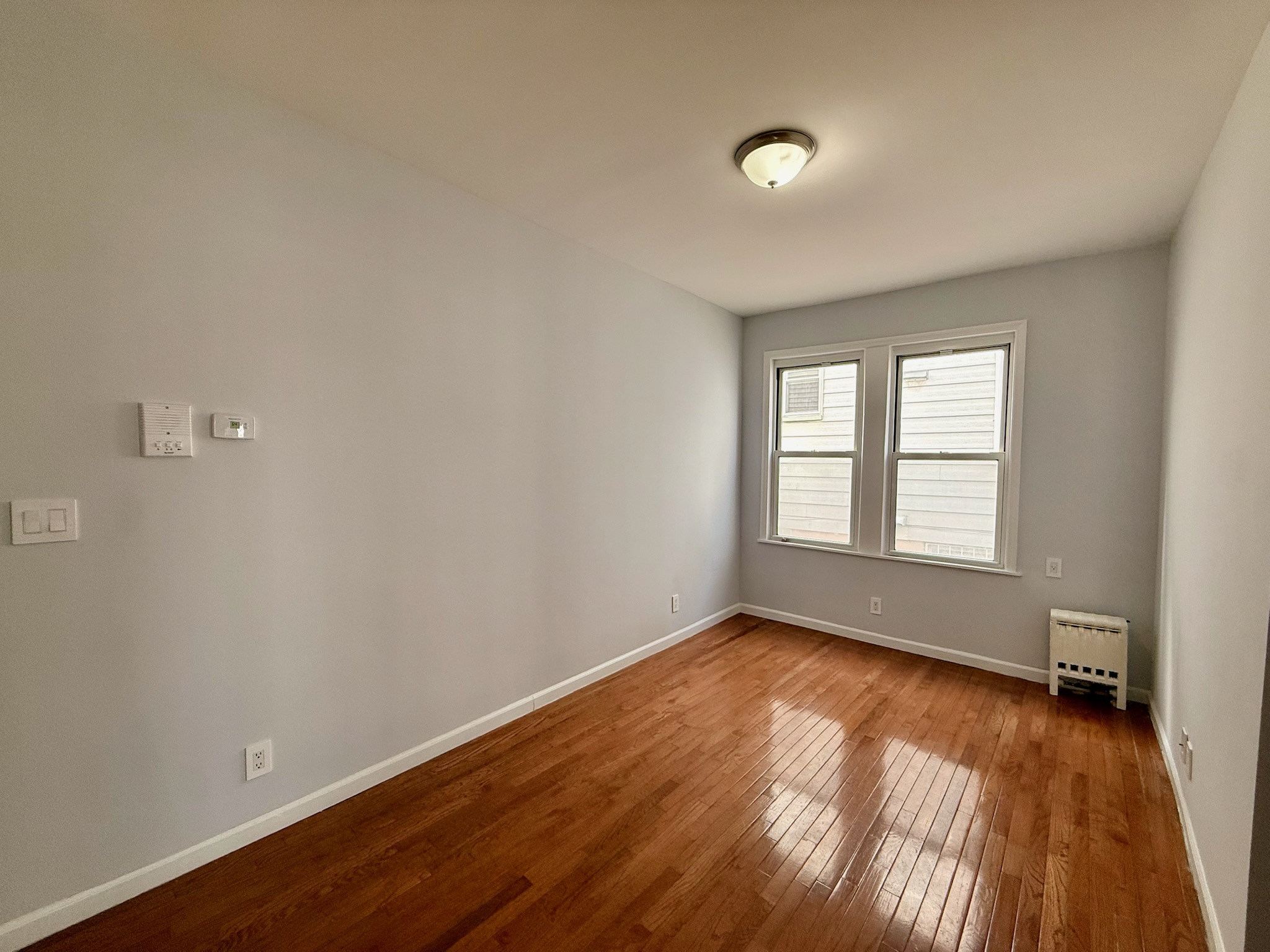 1675 85th Street, Unit 1R Brooklyn, NY 11214 - Photo 6 of 8 an empty room with wooden floor and windows
