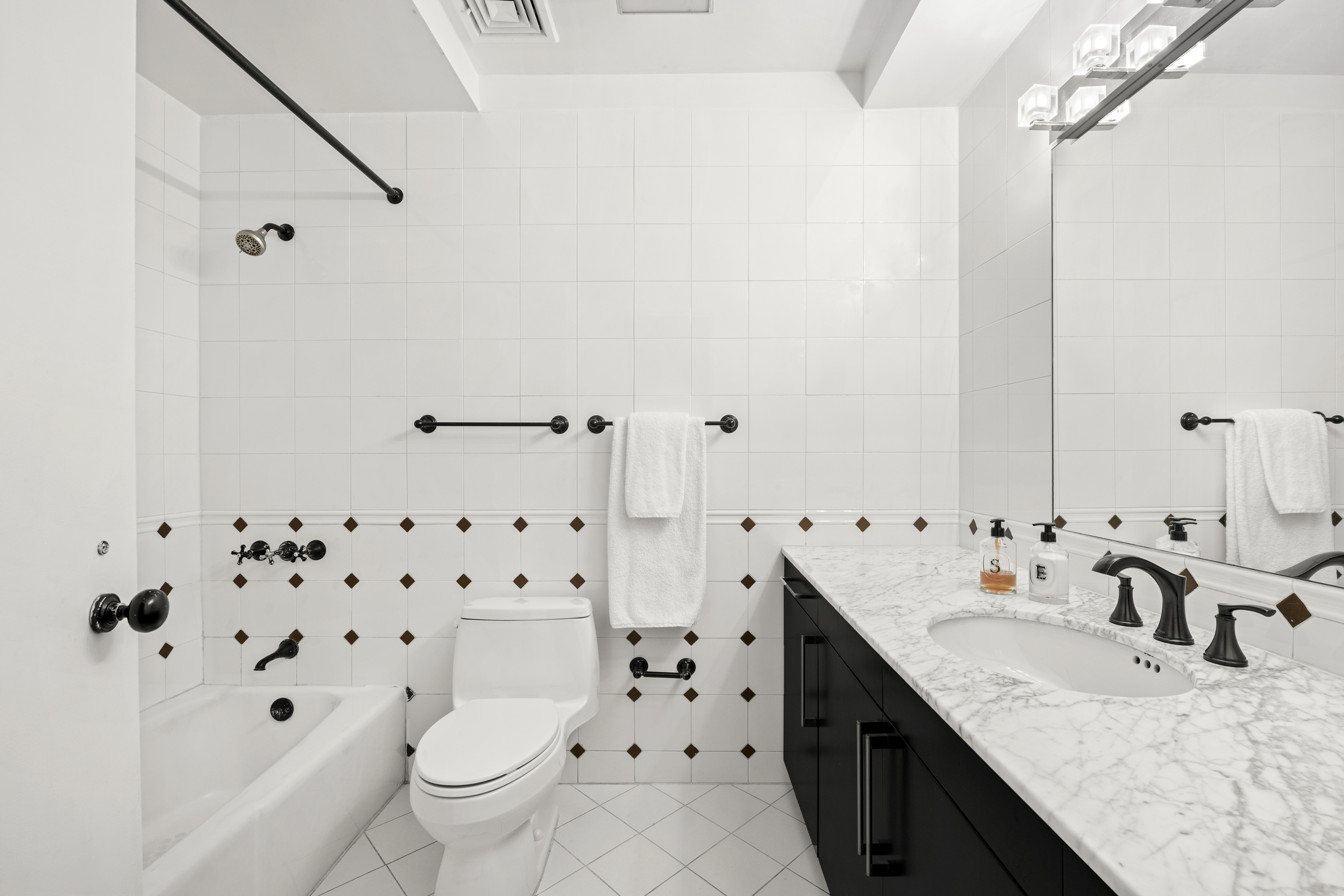 120 West 18th Street, Unit 2A Manhattan, NY 10011 - Photo 12 of 14 a bathroom with a granite countertop sink a toilet a mirror a vanity and shower