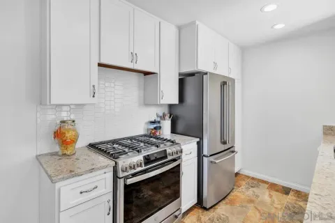 a kitchen with stainless steel appliances granite countertop a stove a refrigerator and a white cabinets