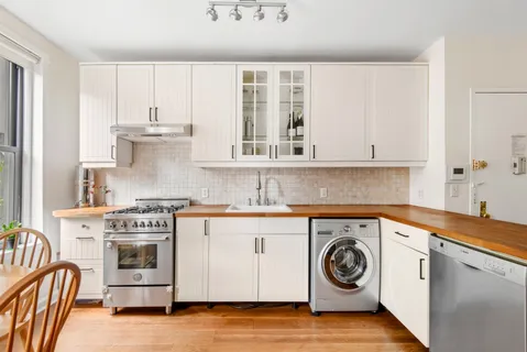 a kitchen with stainless steel appliances granite countertop a stove and a white cabinets
