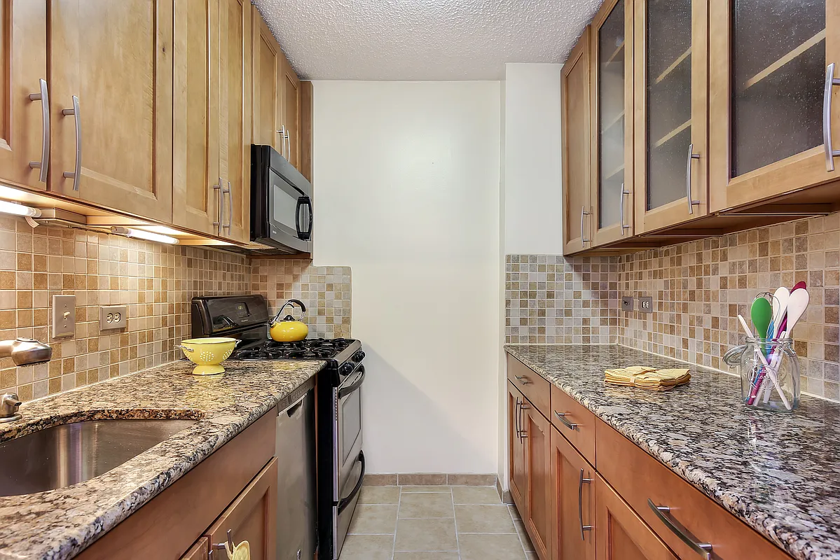 347 West 57th Street, Unit 23A Manhattan, NY 10019 - Photo 2 of 6 a kitchen with granite countertop a sink a stove and cabinets