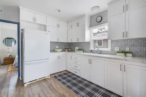 a kitchen with granite countertop white cabinets and white appliances