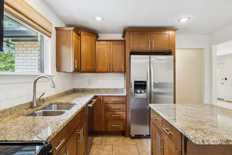 a kitchen with stainless steel appliances granite countertop a sink a stove and a refrigerator