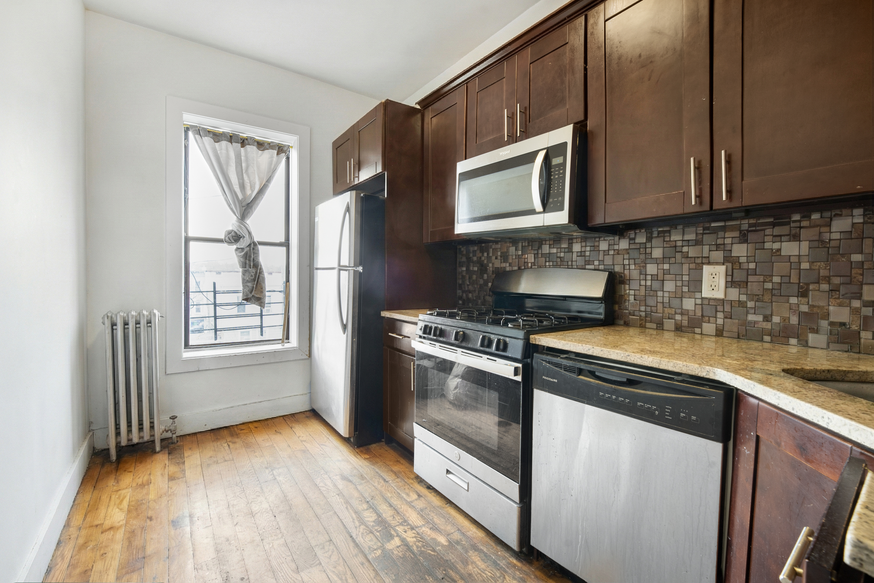 62-22 Myrtle Avenue Queens, NY 11385 - Photo 3 of 13 a kitchen with stainless steel appliances granite countertop a stove a sink and a microwave