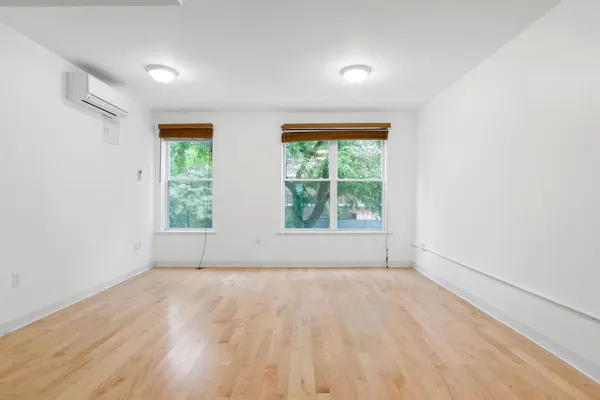 an empty room with wooden floor and windows