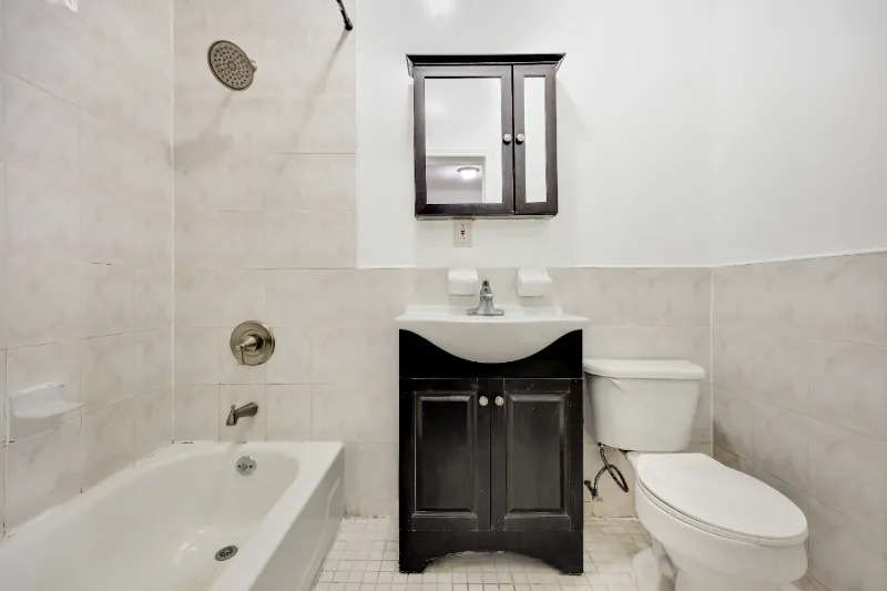 255 Covert Street Brooklyn, NY 11207 - Photo 16 of 18 a bathroom with a toilet sink vanity tub and mirror