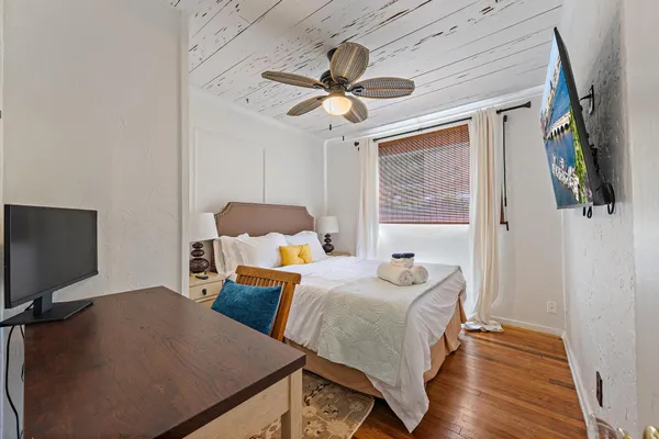 a bedroom with bed tv and a window