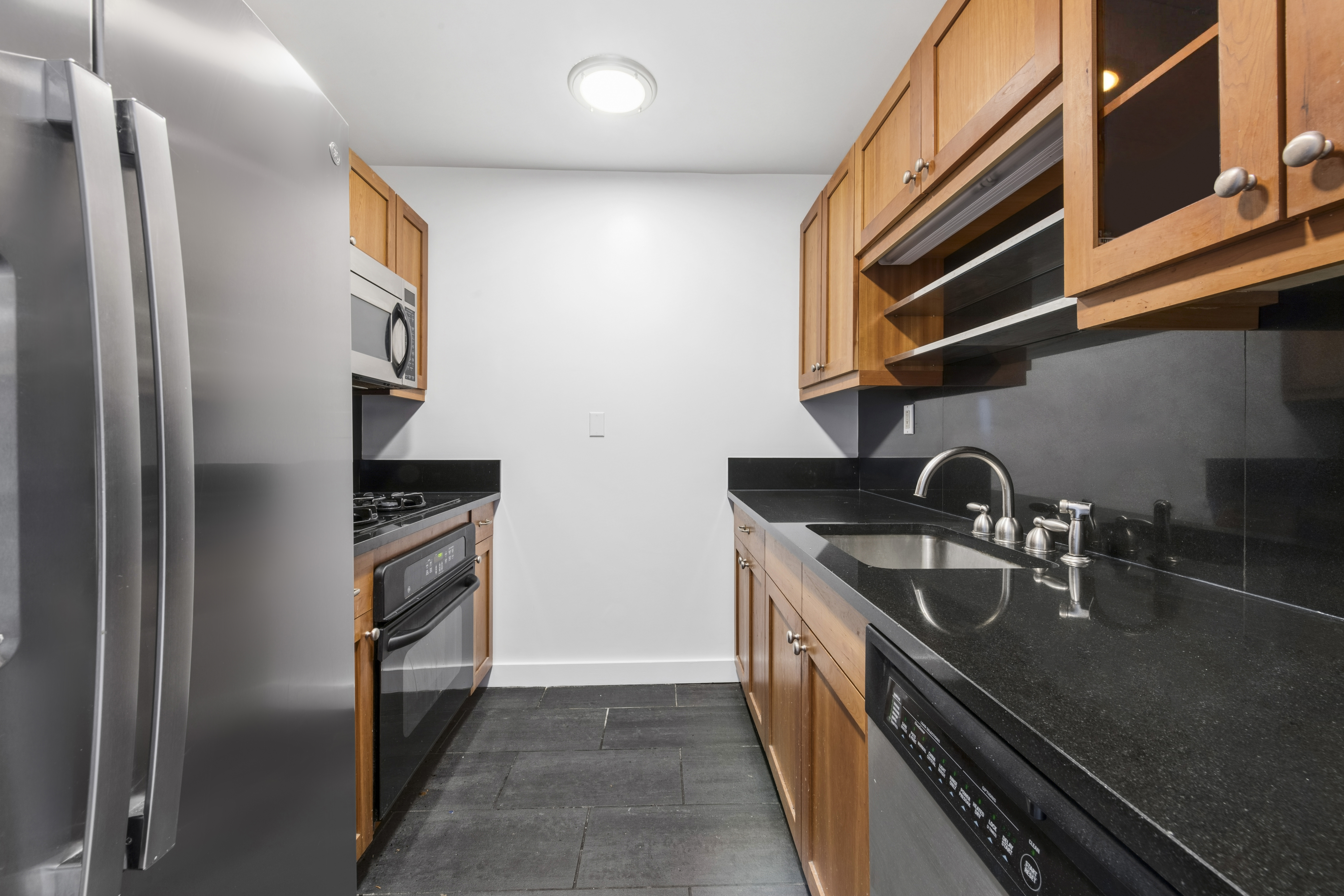 425 5th Avenue, Unit 23D Manhattan, NY 10016 - Photo 10 of 20 a kitchen with stainless steel appliances granite countertop a refrigerator and a sink
