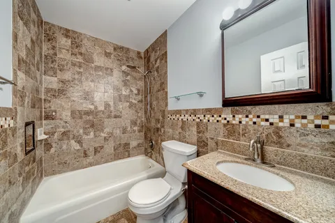 a bathroom with a granite countertop toilet sink and mirror