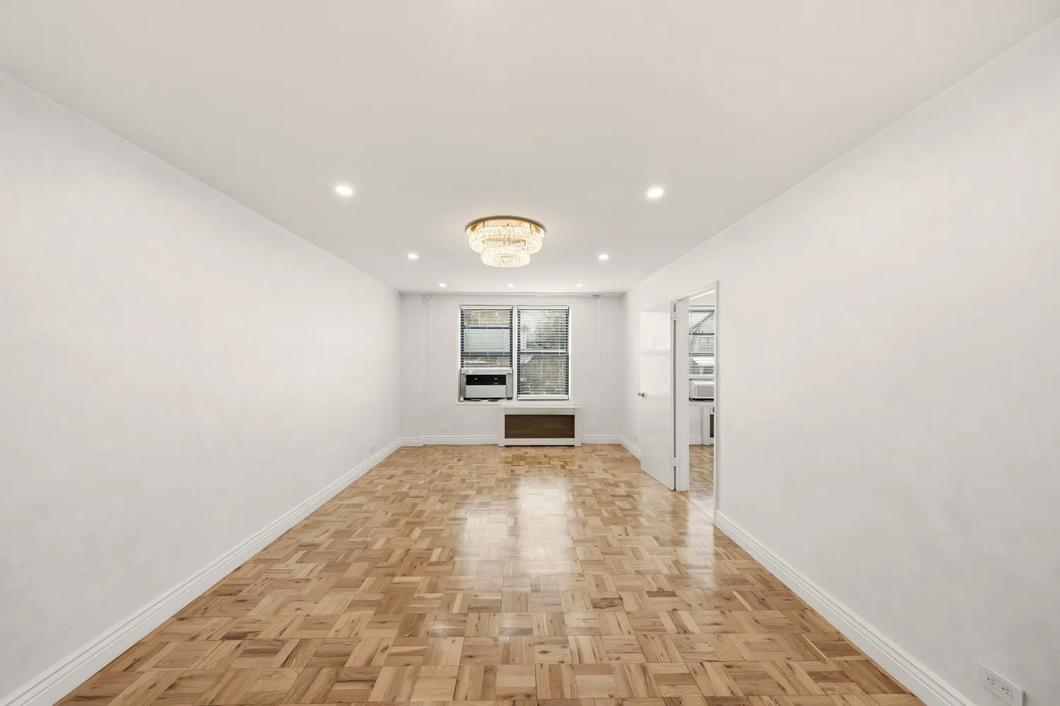 a view of empty room with kitchen and window