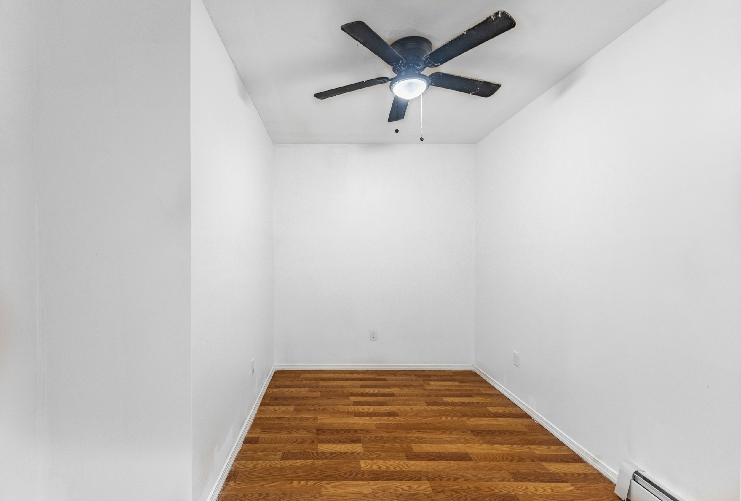 434 Lexington Avenue Brooklyn, NY 11221 - Photo 4 of 22 an empty room with a chandelier fan and wooden floor
