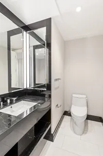 a bathroom with a granite countertop sink a toilet and a mirror