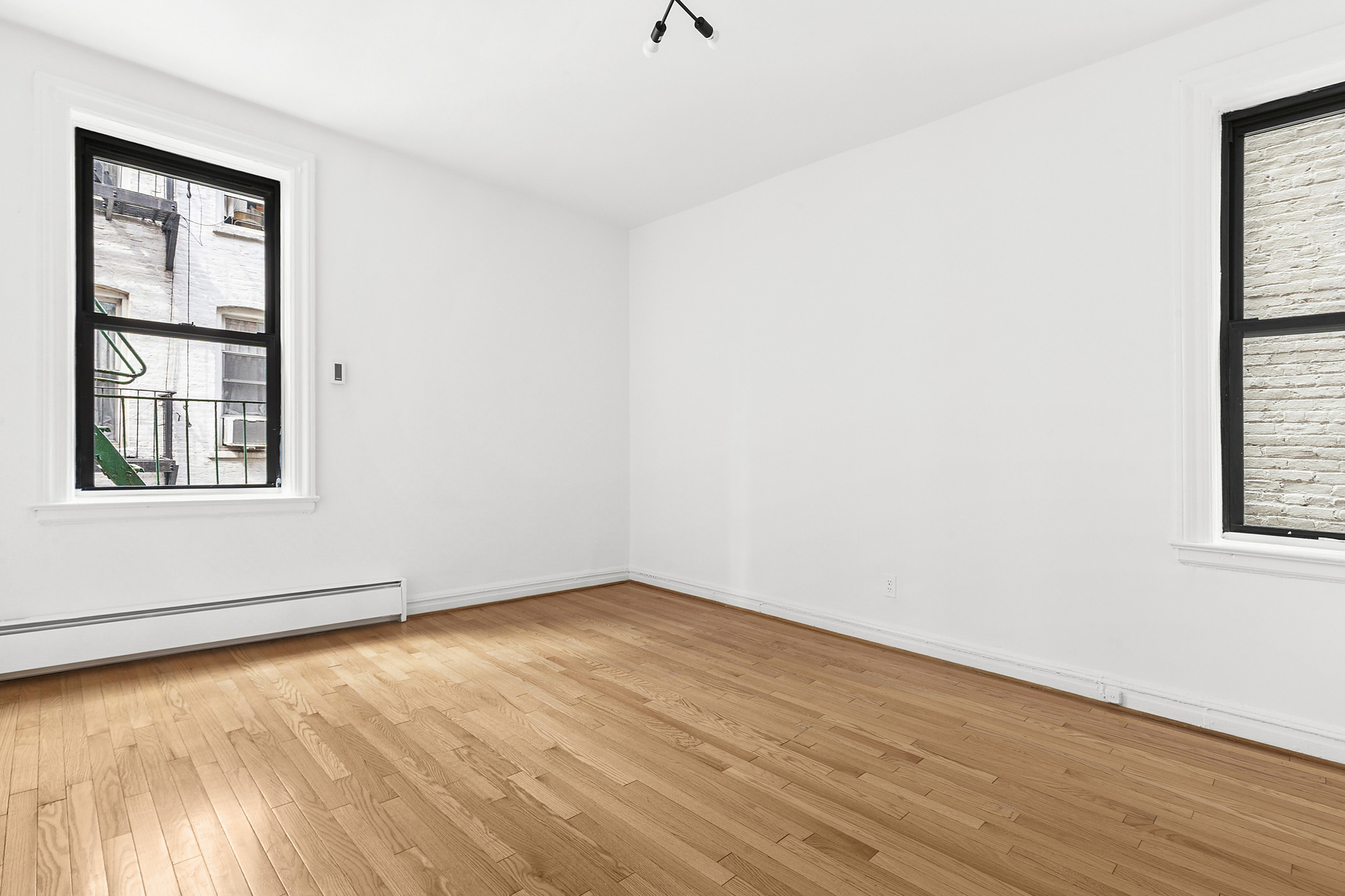 205 West 10th Street, Unit 3D Manhattan, NY 10014 - Photo 4 of 7 an empty room with wooden floor and windows
