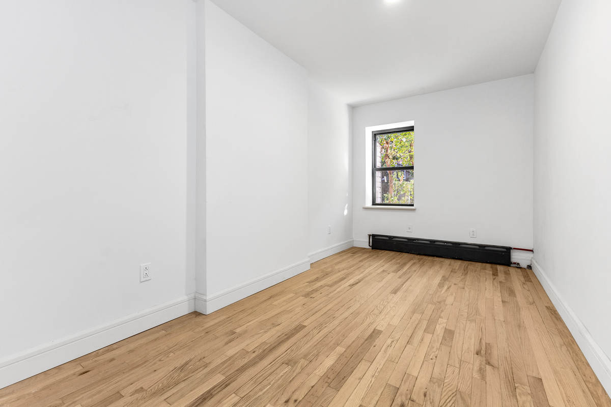 574 Gates Avenue Brooklyn, NY 11221 - Photo 12 of 16 an empty room with wooden floor and windows