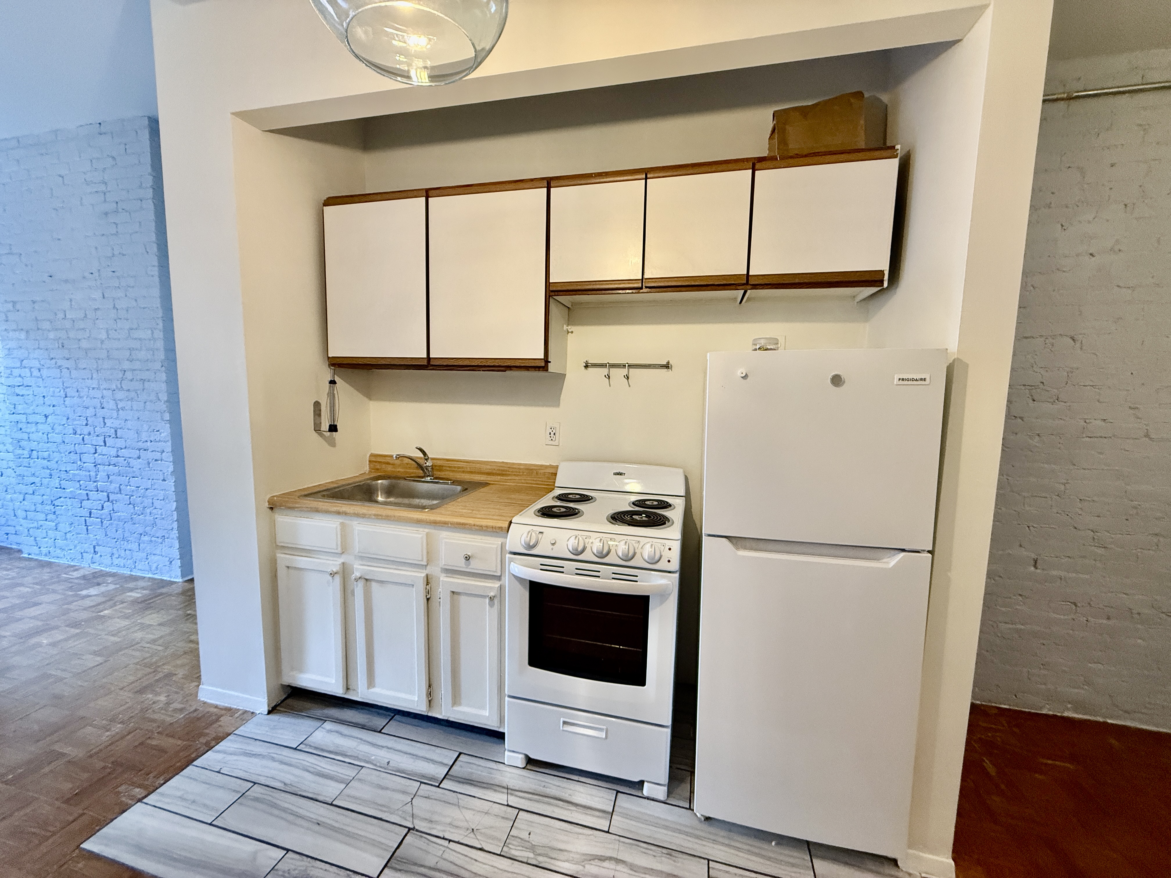 344 East 61st Street, Unit 16 Manhattan, NY 10065 - Photo 5 of 8 a kitchen with a stove a sink and a refrigerator