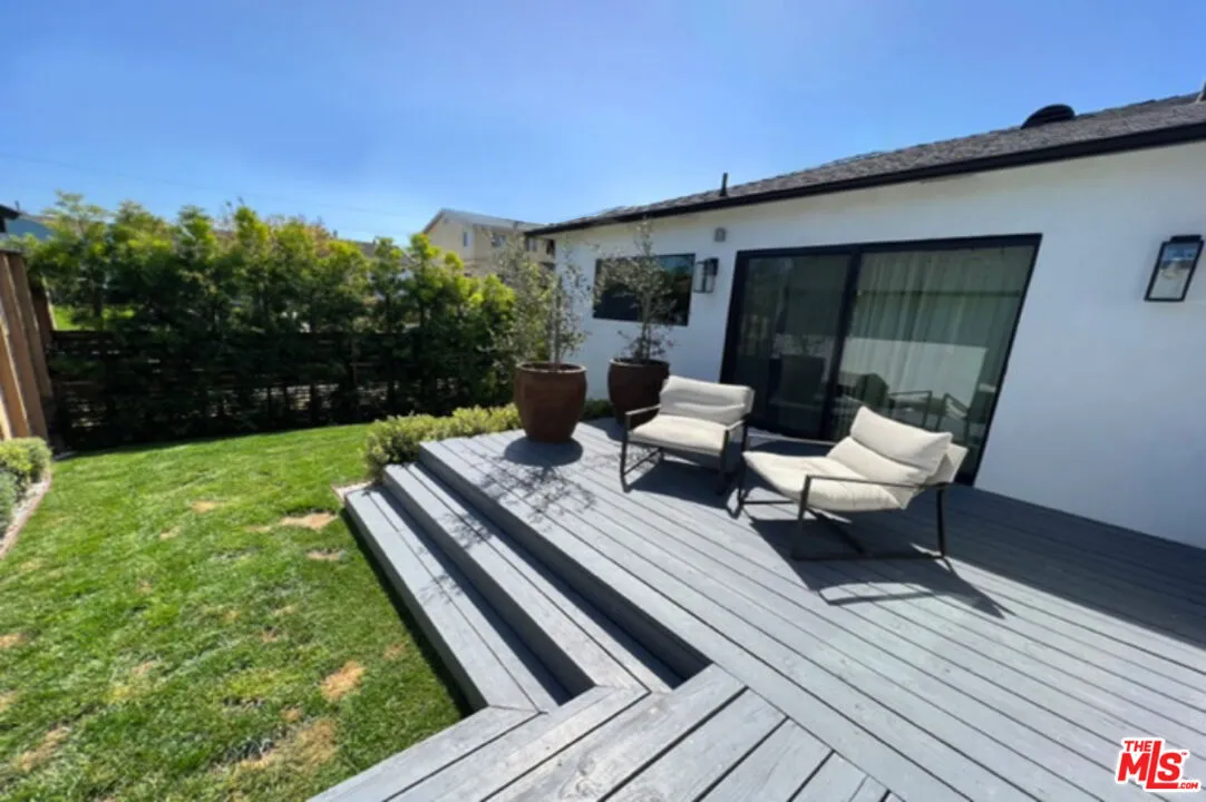 a view of a patio with table and chairs with wooden floor and fence