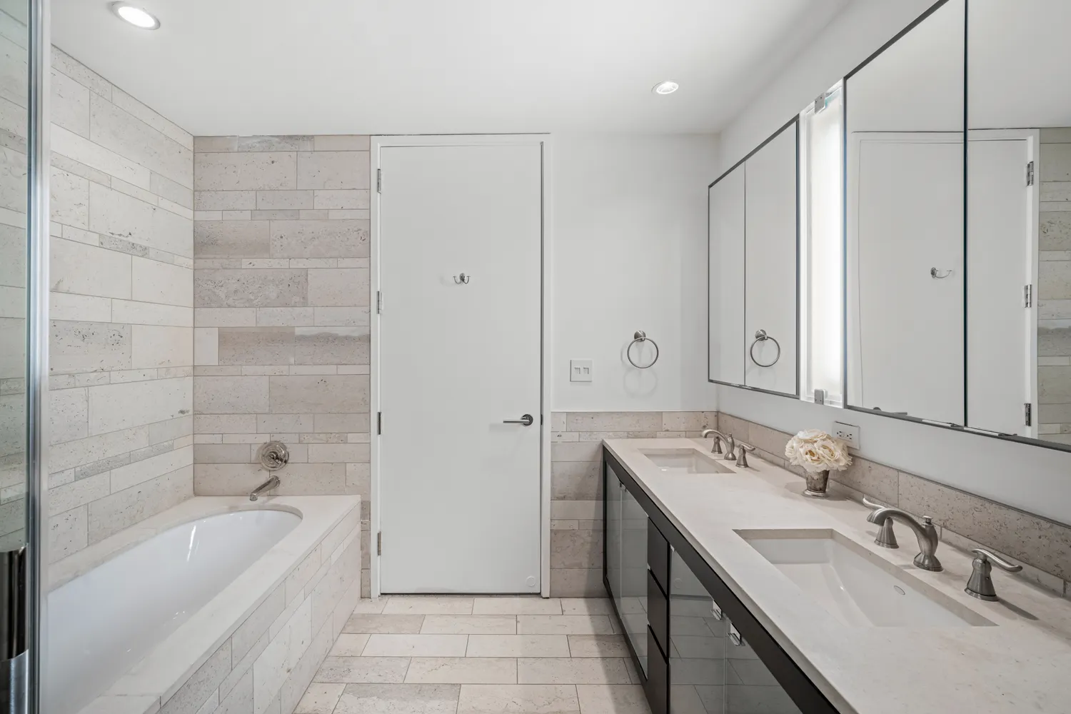 a bathroom with a tub sink double vanity granite tub shower and mirror