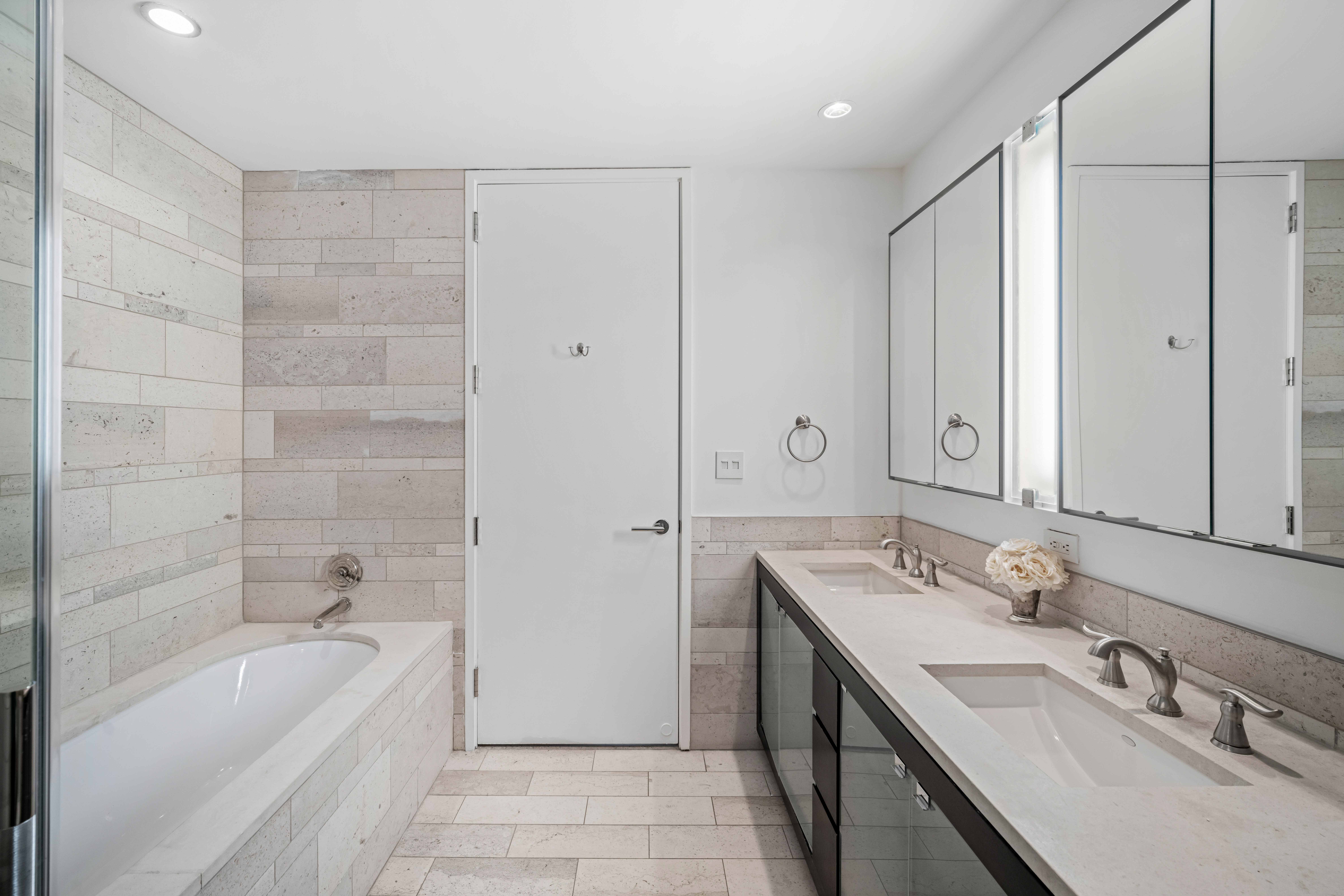 450 East 83rd Street, Unit 9E Manhattan, NY 10028 - Photo 8 of 18 a bathroom with a tub sink double vanity granite tub shower and mirror