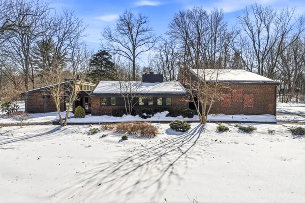 a front view of a house with a yard covered in snow