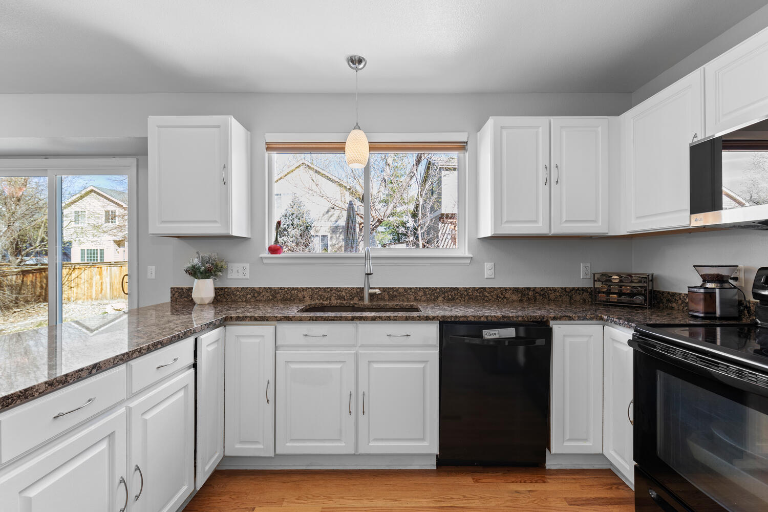 847 Timbervale Trail Highlands Ranch, CO 80129 - Photo 18 of 36 a kitchen with granite countertop white cabinets and black stainless steel appliances