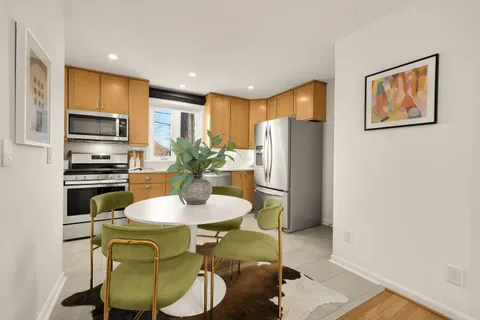 a kitchen with stainless steel appliances a refrigerator a stove a microwave a dining table and chairs with wooden floor