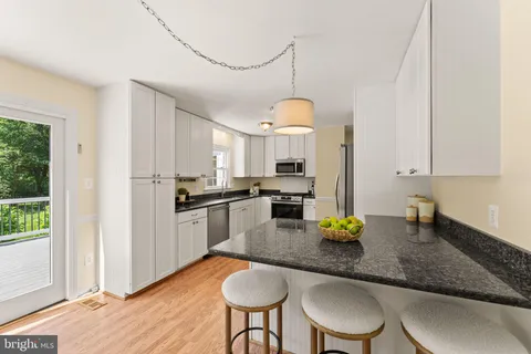 a kitchen with stainless steel appliances granite countertop a stove a refrigerator a sink a stove and island with wooden floor
