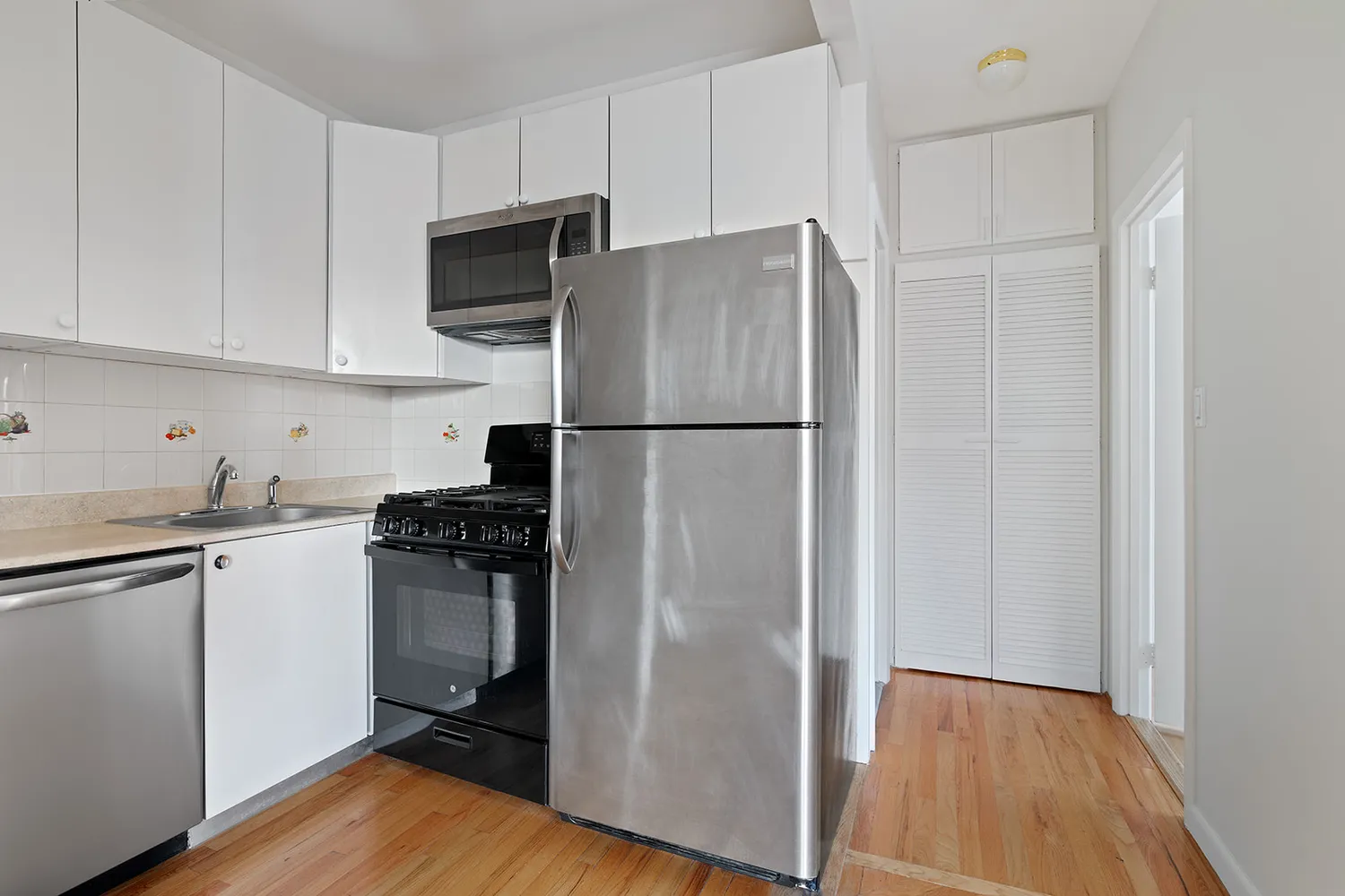 a kitchen with cabinets stainless steel appliances and wooden floor