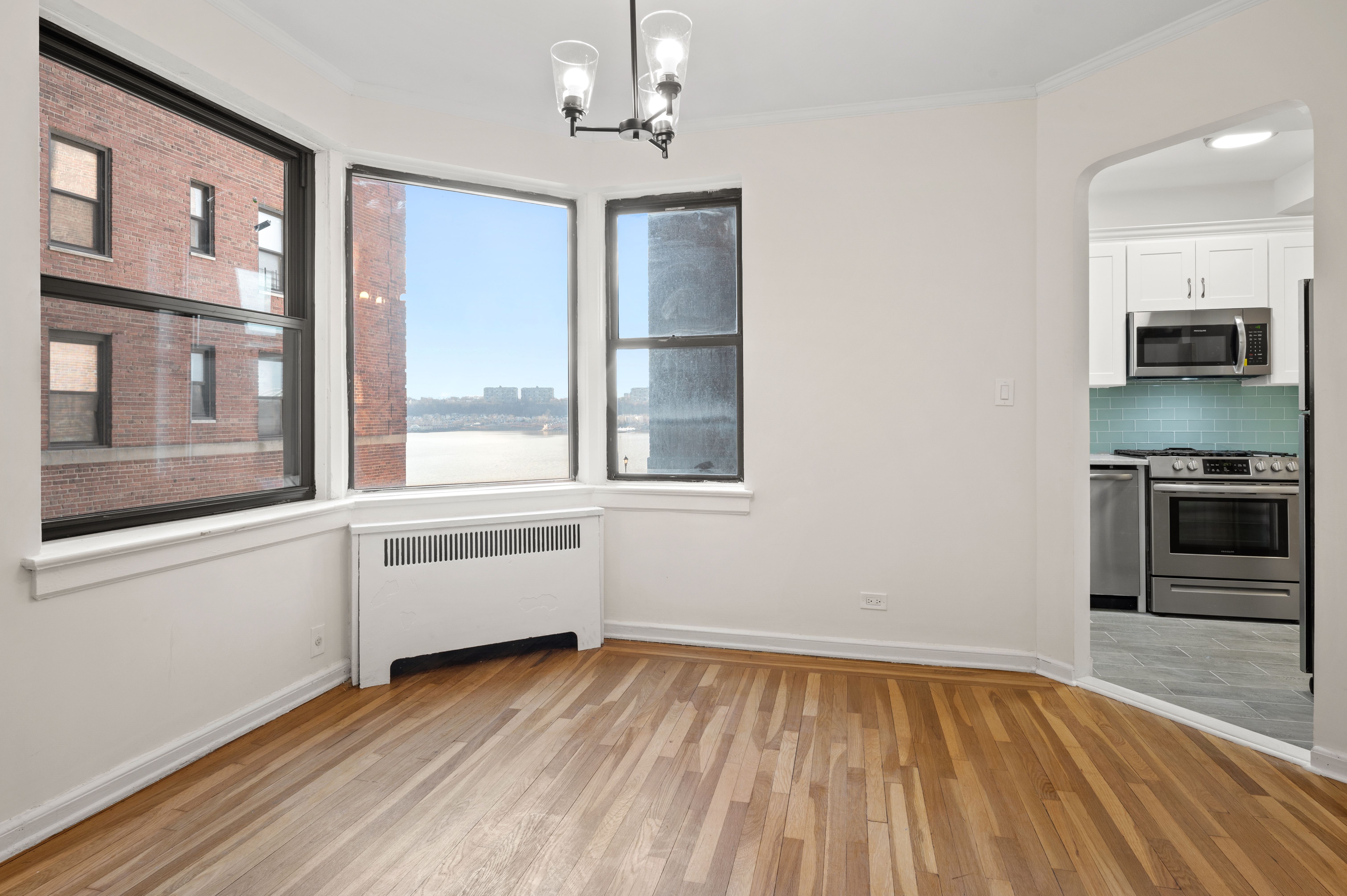 159-34 Riverside Drive West, Unit 3D Manhattan, NY 10032 - Photo 2 of 12 a view of a kitchen and an empty room with wooden floor and a window