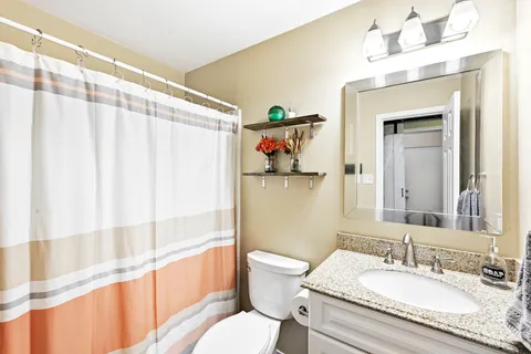 a bathroom with a granite countertop sink a toilet and a large mirror