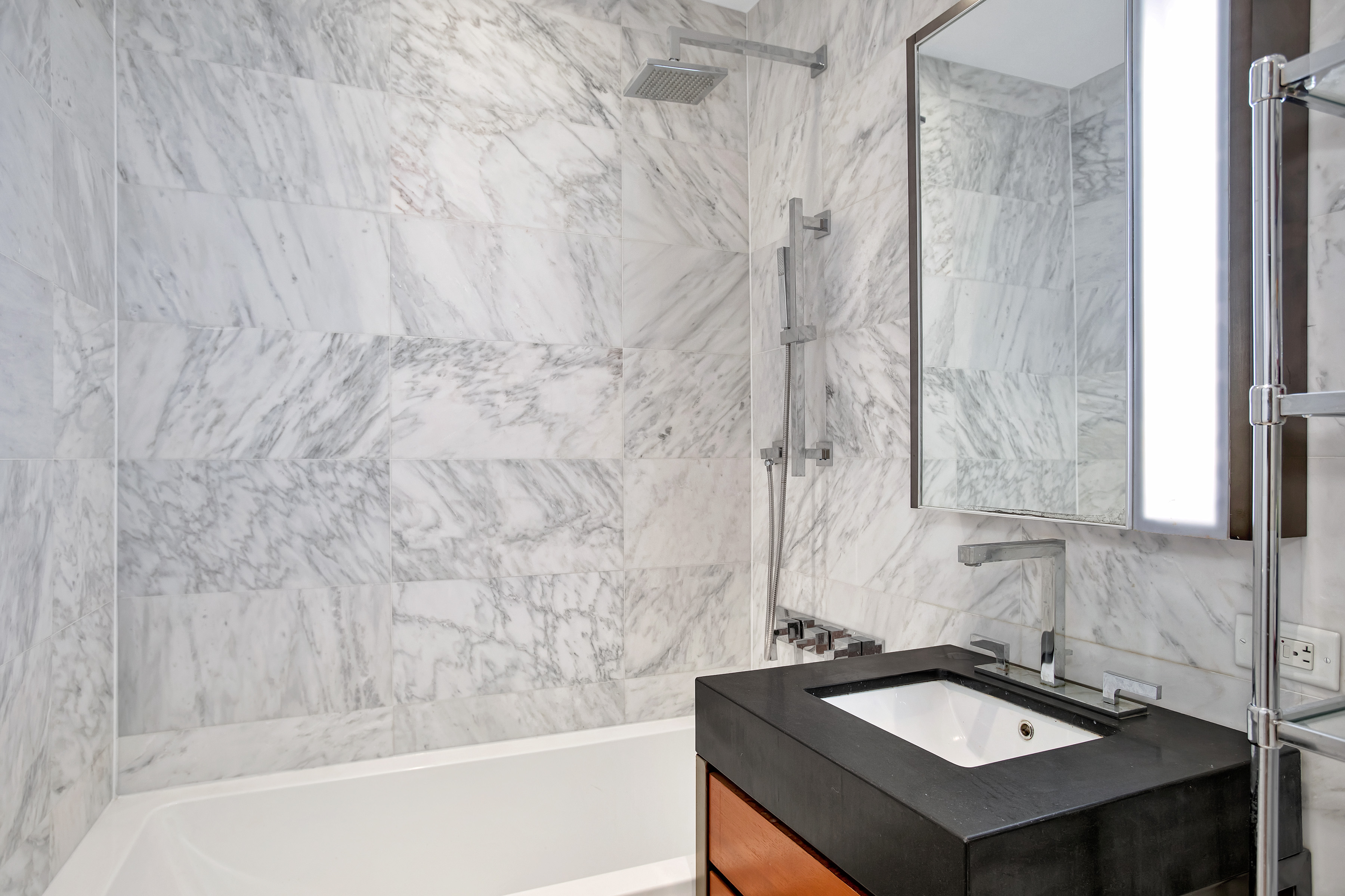 75 Wall Street, Unit 26D Manhattan, NY 10005 - Photo 4 of 11 a bathroom with a sink a mirror and a bathtub